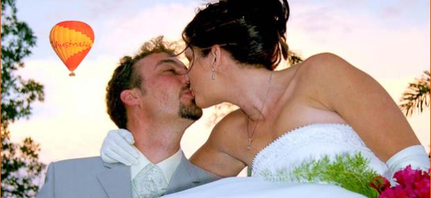 Bride and Groom kiss with hot air balloon in the background